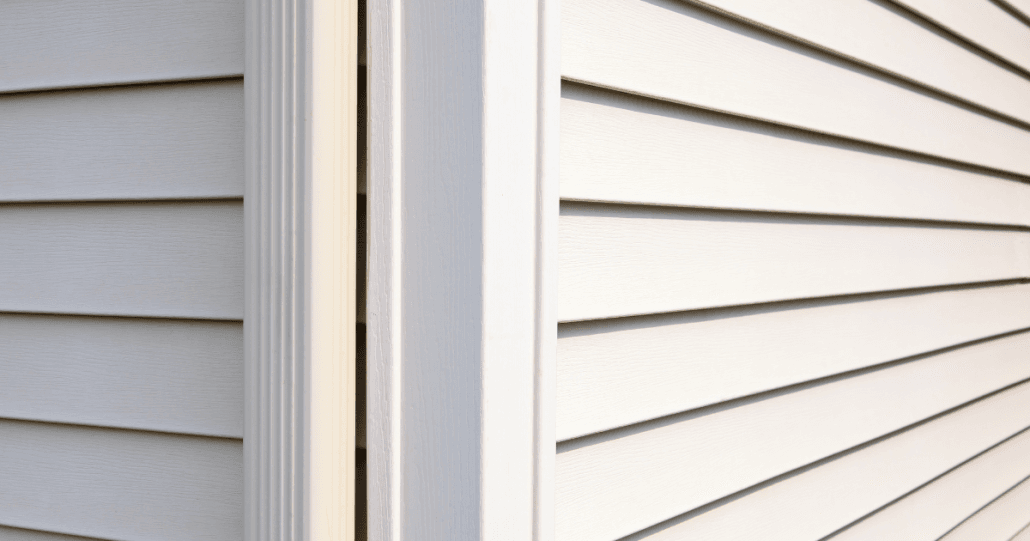 Close-up of a building corner with beige vinyl siding. The horizontal lines create a clean, orderly pattern, conveying a sense of modernity and simplicity.