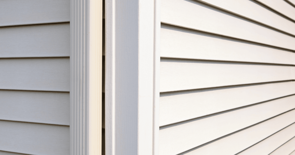 Close-up of beige vinyl siding on a house corner, with horizontal panels neatly aligned. The clean lines convey a sense of order and simplicity.