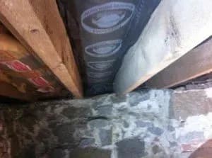 Stone basement wall with exposed wooden beams and insulation. The stonework conveys a rustic atmosphere, while the insulation suggests ongoing construction.