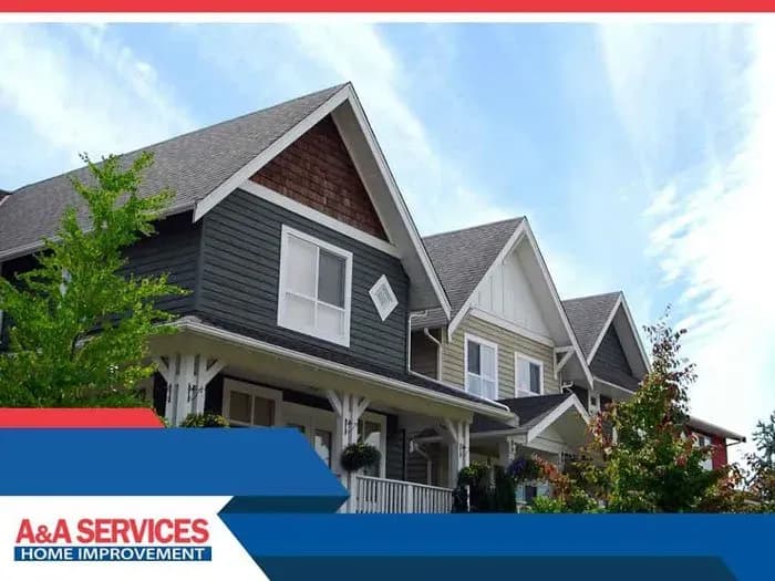 Row of modern homes with gable roofs against a blue sky, surrounded by green trees. A&A Services Home Improvement branding is in the corner.