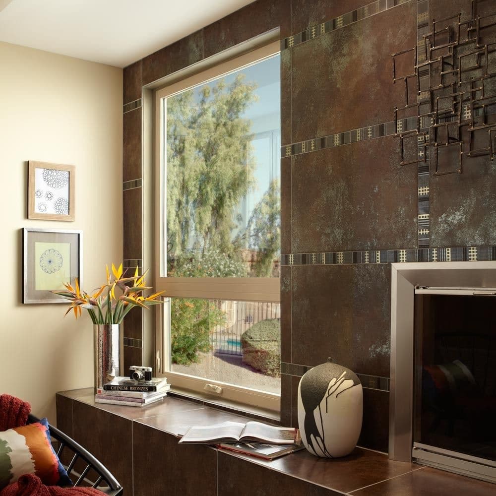 A cozy room with a large window showing a sunny outdoor view. Inside, a vase with flowers is on a shelf beside books, against brown textured walls.