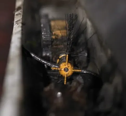 Close-up of a small, worn-out toy tractor in a muddy, narrow channel. The setting appears dark and gritty, evoking a sense of abandonment.