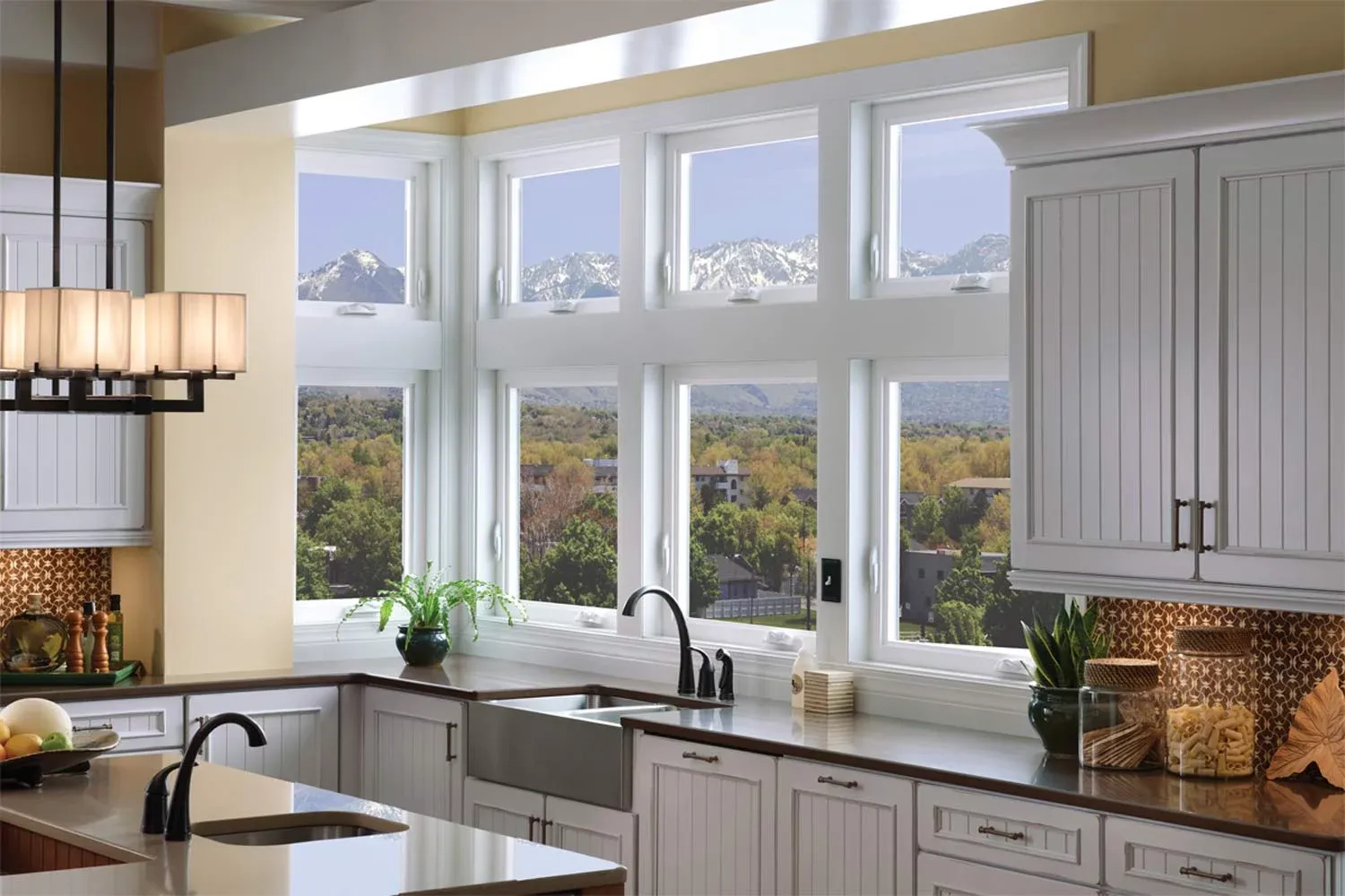Bright kitchen with white cabinets, a modern sink, and a large window showcasing a stunning mountain view. The room feels airy and inviting.