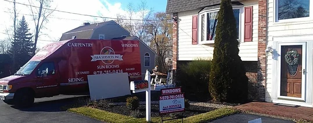 A red van labeled "A&A Services Inc." for carpentry and windows is parked beside a house. A lawn sign advertises window services, indicating ongoing renovations.
